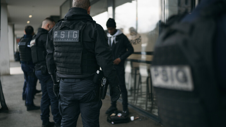 Quatre gendarmes procèdent au contrôle d'un piéton au pied de batiment