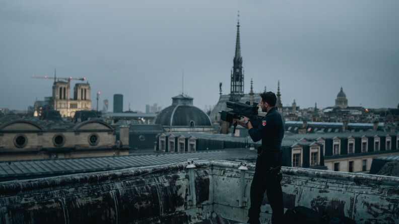 Un gendarme sur un toit de Paris, tient une sorte de fusil noir qui sert &agrave; neutraliser de potentiel drone.