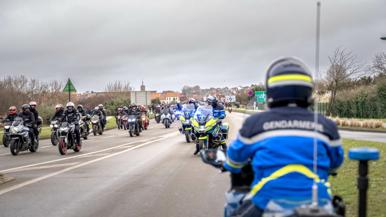 Trois motards de la gendarmerie décalent sur une voie des dizaines de motards de l'Enduropale. Au fond, des maison au toit orange