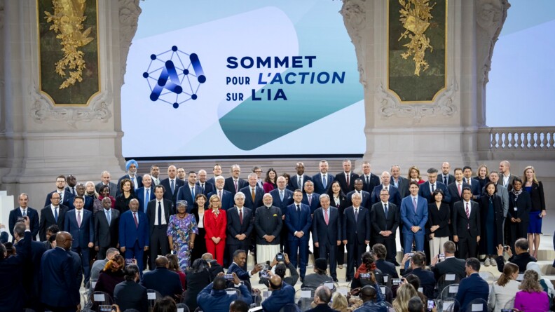 Photo de nombreux dirigeants de différents pays, posant debout devant un écran sur lequel est inscrit "Sommet pour l'action sur l'IA"