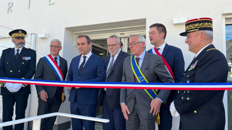 Le ministre des Armées, entouré des autorités civiles et militaires, devant le ruban inaugural tendu à l'entrée d'un bâtiment.