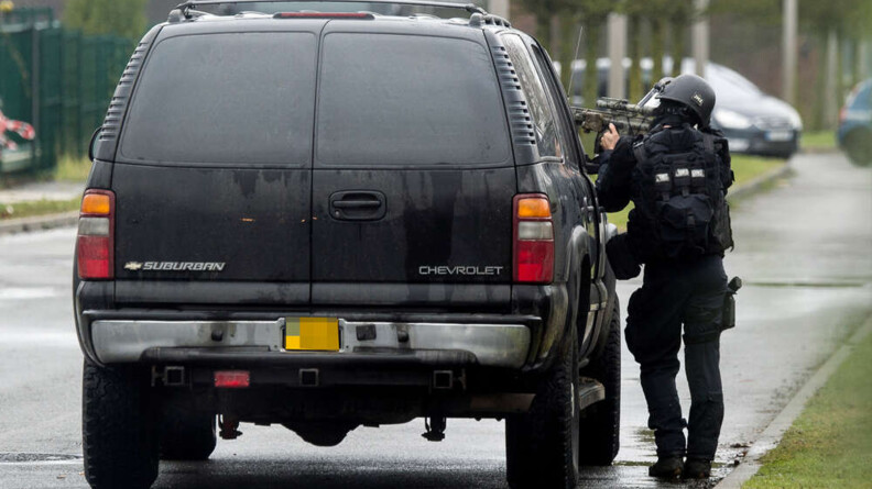 Agrandir l'image Un opérationnel du GIGN abrité derrière un véhicule noir Suburban Chevrolet pointe un fusil.