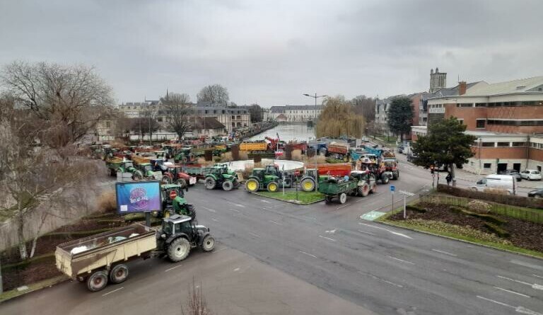 Vue de haut de plusieurs dizaine de tracteurs dans les rues d'une ville.