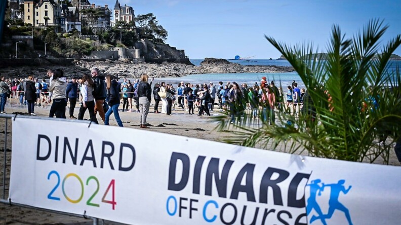 Banderole Dinard Off Course devant la plage de Dinard et la mer, avec de très nombreuses personnes sur la plage.