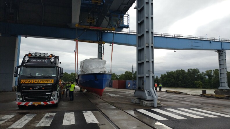 La nouvelle vedette de la compagnie fluviale franco-allemande entrain d'être descendue du camion sur le sol.
