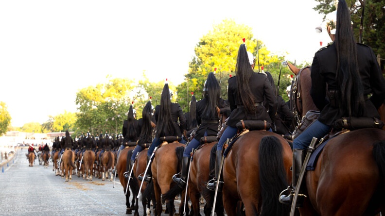 Les cavaliers du Régiment de cavalerie de la Garde républicaine, de dos, se dirigent vers la tribune présidentielle