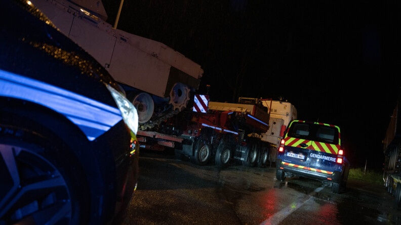 Deux voitures de gendarmerie devant le convoi. Il fait nuit.