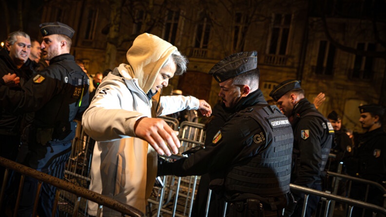 Gendarme mobile effectuant une palpation sommaire à l'entrée de la zone sécurisée autour des Champs-Élysées.