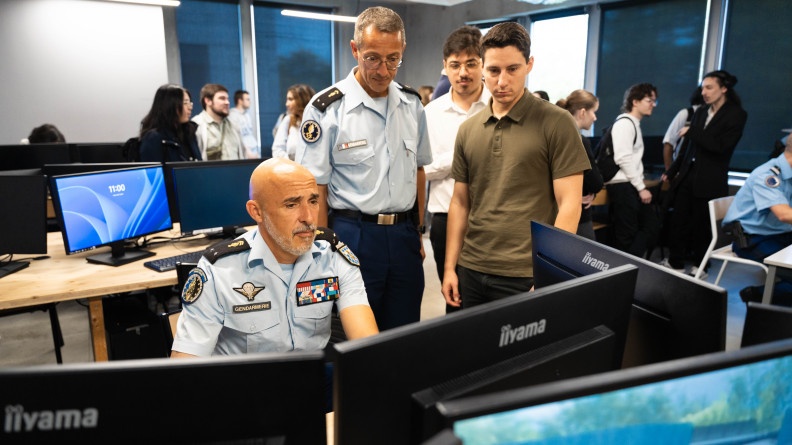Deux g&eacute;n&eacute;raux pris de face sont sur un ordinateur en train de d&eacute;couvrir la nouvelle plateforme. A c&ocirc;t&eacute; d'eux, deux &eacute;l&egrave;ves regardent.