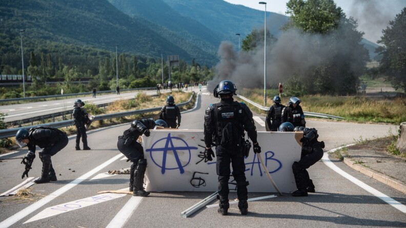 Un groupe de gendarmes mobiles en train de dégager les barricades sur la route.