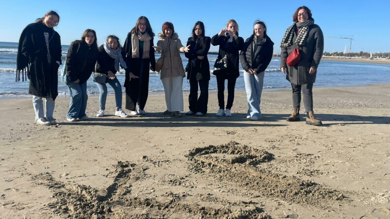 Un groupe de six adolescentes et deux mamans posent sur la plage devant la mer apr&egrave;s avoir &eacute;crit les lettres K et P, pour l'association K&eacute;pis pescalunes, dans le sable.