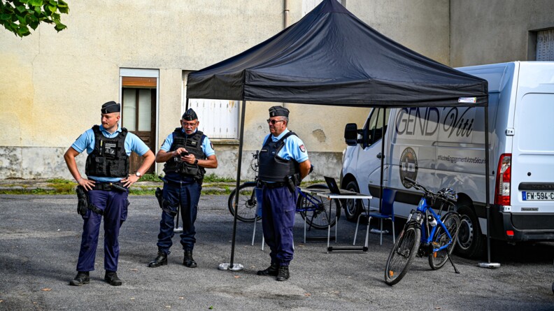 Trois gendarmes debout. Juste derrière sur la droite, une tonnelle carré noire au dessus d'une table avec ordinateur. De part et d'autres des vélos de gendarmes. A droite, derrière la tonnelle, un véhicule blanc avec l'inscription "Gend Viti"