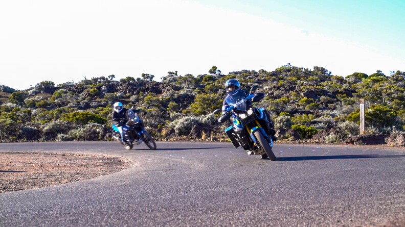 Sur la route, un motocycliste de la gendarmerie ouvre la voie. Derrière lui, un motard, civil le suit.