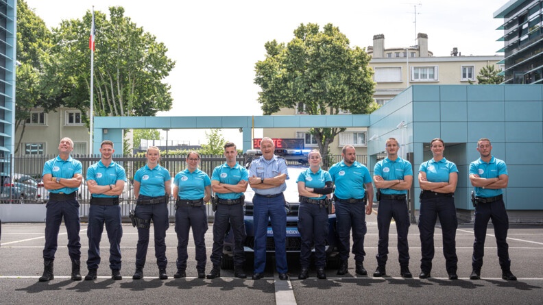 Les membres de la caravane du Tour de France de part et d'autre du Directeur g&eacute;n&eacute;ral de la gendarmerie nationale, devant un v&eacute;hicule gendarmerie du Tour de France