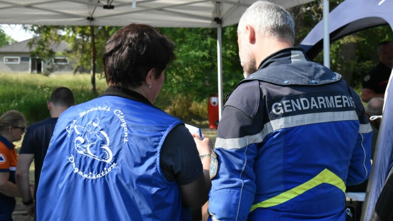 Une membre de l'association "les motards citoyens" et un motocycliste de l'EDSR 78, vus de dos, en train de discuter. En arri&egrave;re-plan, &agrave; gauche, une personnel de la Protection civile et un homme vu de dos.
