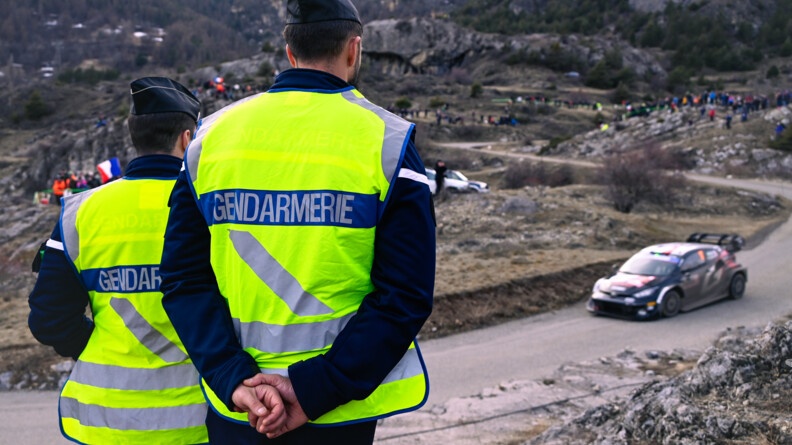 Deux gendarmes regardent une voiture du Rallye entrain de passer lors d'une des spéciales.