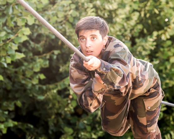 Agrandir l'image Une jeune militaire, aux cheveux châtains coupés courts, en tenue camoufage, réalise un exercice sur une corde
