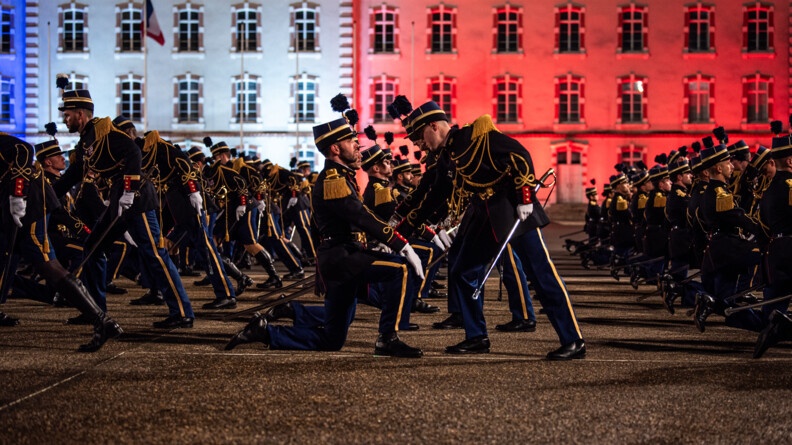 Agrandir l'image Les nouveaux élèves-officiers alignés, un genou au sol et main sur l'autre, face à leurs parrain qui saisissent le pommeau de leur sabre