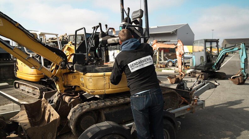 Un gendarme en civil avec dans le dos écrit "gendarmerie section de recherches". Il se trouve devant un tracteur.