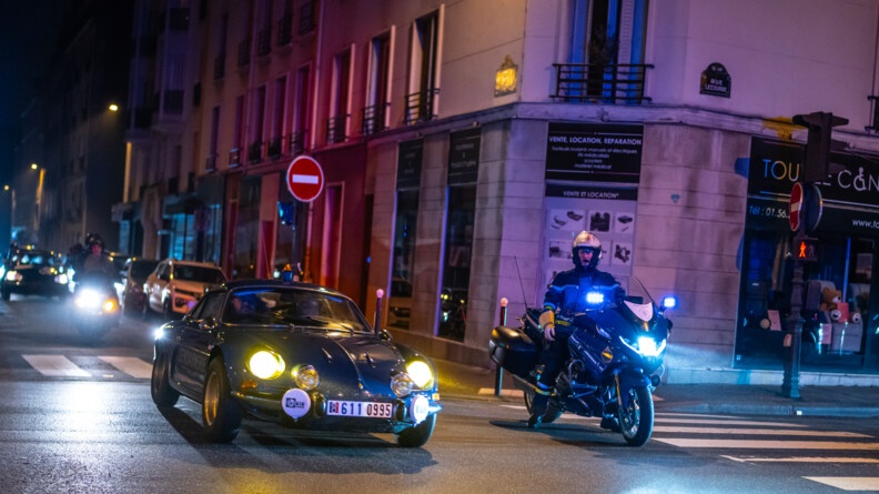 Agrandir l'image Un gendarme en moto de nuit devant des véhicules de collection
