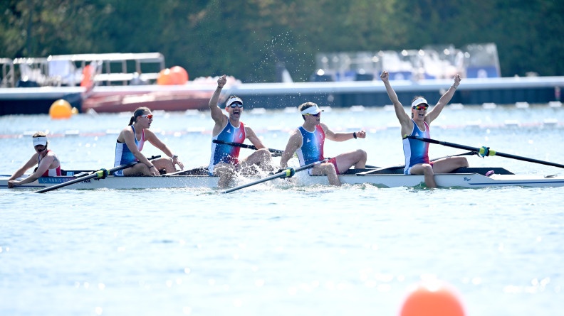 L'équipage français de para-aviron sur leur embarcation. Ils sont vêtus d'un débardeur tricolore, d'une casquette et de lunettes de soleil. Trois d'entre eux lèvent les bras au ciel en signe de victoire. A l'avant du bateau, Margot Boulet.