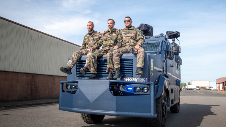 Un équipage de 3 personnels sur le capot d'un centaure, souriants