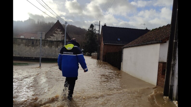 Un gendarme entrain de marcher dans une rue inond&eacute;e
