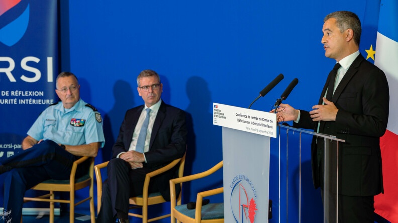 Agrandir l'image A droit, le minsitre de l'intérieur et des outre-mer, Gerald Darmanin, s'exprime derrière un pupitre pour la conférence de rentrée du Centre de réflexion sur la sécurité intérieure (CRSI). A gauche de l'image, assis sur des chaises et le regardant, un homme en costard et le Directeur général de la gendarmerie nationale