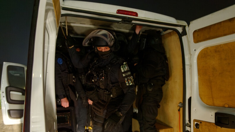 Photo d'un groupe d'intervention, dans leur tenue, sortant du coffre d'un camion.