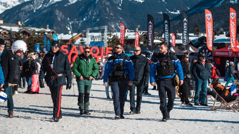 Sur le site de Courchevel le Praz, les gendarmes mobiles sécurisent la zone acceuillant du public. Pour les accompagner sur cet événement de portée internationale, ils sont appuyés par des carabiniers italiens, des gendarmes de la Garde civil et des policiers de la Polizei allemande. Tous patrouillent ensemble sur la neige au milieu du public avec en toile de fond la montagne savoyarde.