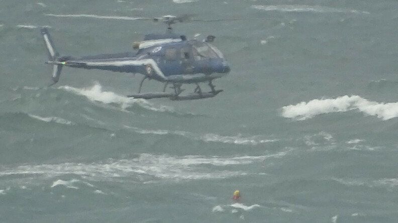 Agrandir l'image Un hélicoptère gendarmerie est en vol stationnaire au dessus de la mer. La mer est agitée et une personne est à l'eau