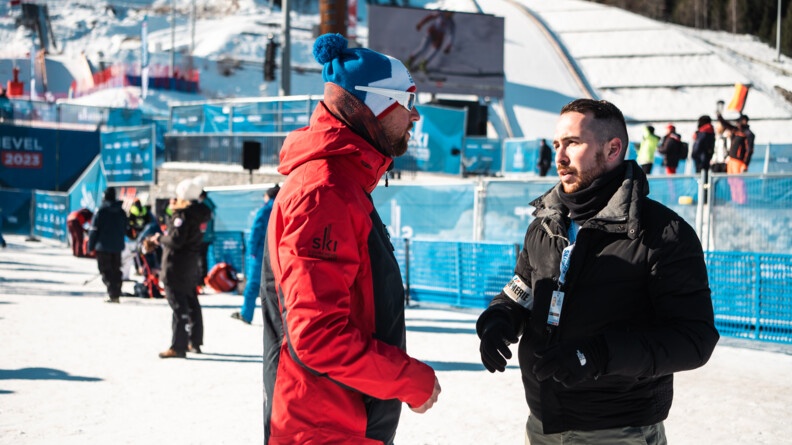 Le TSLO, un gendarme mobile habillé en civil avec un brassard gendarmerie est entrain de parler à un membre d'une délégation étrangère devant la grande piste de Courchevel. Cela, à l'occasion des championnats du monde de Courchevel.