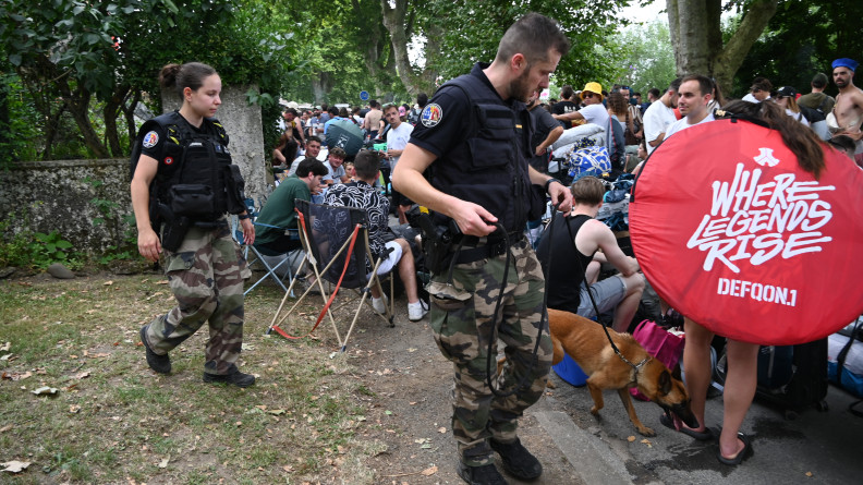 La photo représente des gendarmes (un homme et une femme), accompagnés d'un malinois, au milieu de la foule, à l'occasion du festival Garorock