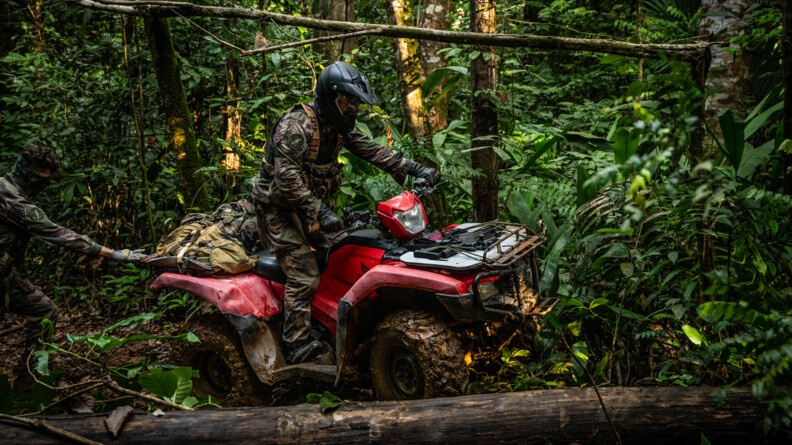 Militaire pilotant son quad à l'approche d'un tronc.
