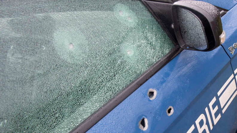 Agrandir l'image Gros plan sur trois impacts de balles sur la portière avant-droite d'un véhicule de gendarmerie, et trois autres sur la vitre.