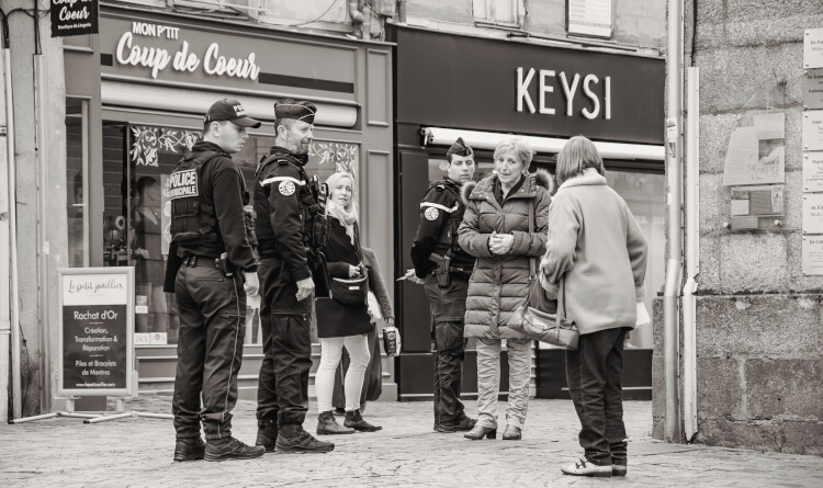 Agrandir l'image 2 gendarmes et un policier discutant avec 3 femmes dans la rue. La photo est en noir et blanc.