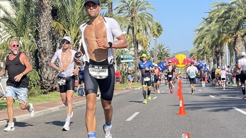 Agrandir l'image Au premier plan, le MDC Guillaume en action de course sur la promenade des Anglais. Derrière lui, d'autres coureurs foulent le bitume de cette avenue bordée de palmiers, sous lesquels sont massés des spectateurs.