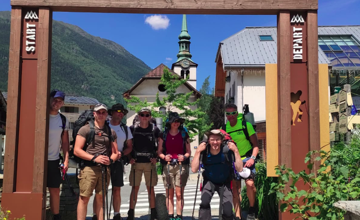 Le groupe de randonneurs r&eacute;unis sous l'arche marquant le point de d&eacute;part du Tour du Mont Blanc dans le village des Houches.