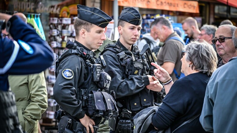 Deux gendarmes mobiles renseignent une passante au milieu de la foule.