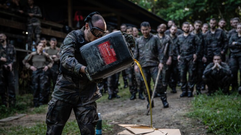 Militaire arrosant les éléments à détruire d'huile pour faciliter la mise à feu.