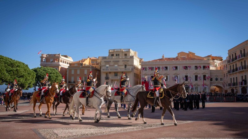 Un détacheent de militaires de la musique de la garde républicaine sur une place, devnat du public et devat des batiment clairs