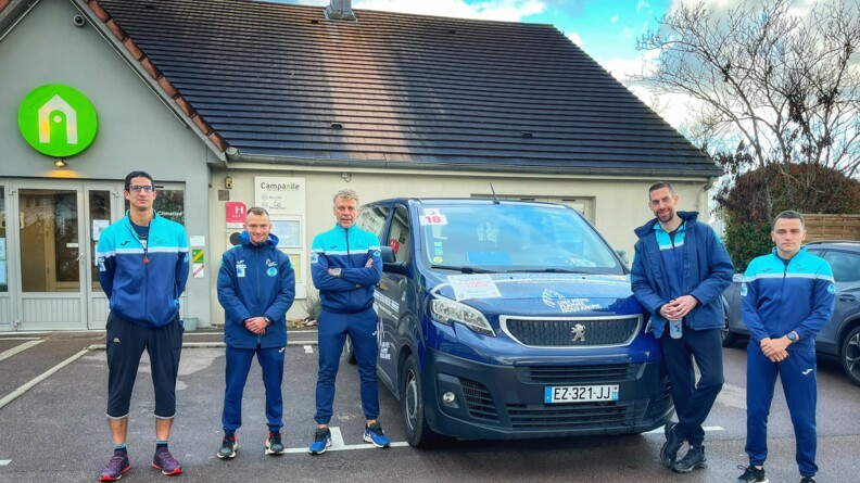 Cinq membres de l'équipe de la gendarmerie pour la course du coeur, devant leur hôtel, avec le véhicule de la gendarmerie.