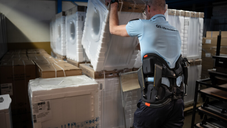 Un gendarme fait basculer un lave linge sous bliester, &eacute;quip&eacute; d'un exosquelette lombaire
