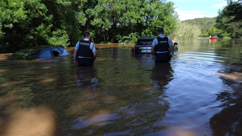 Deux gendarmes progressant avec de l'eau jusqu'aux genoux vers deux v&eacute;hicules.