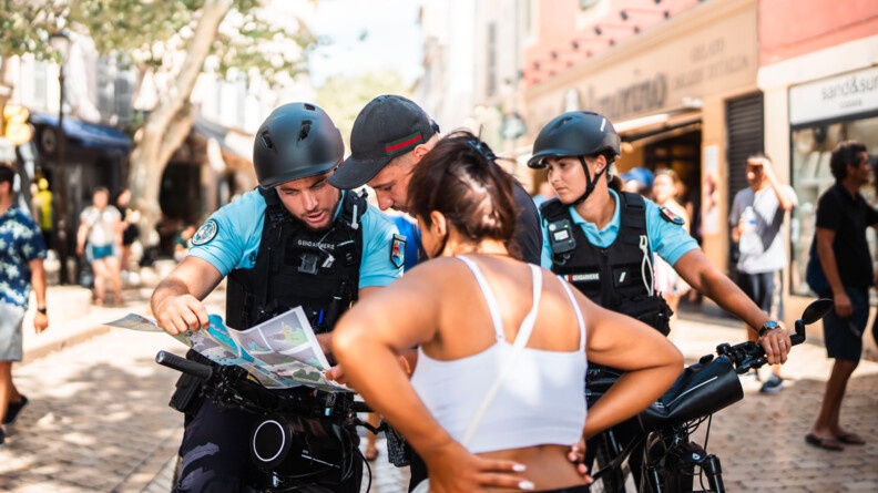 Les gendarmes indiquant le chemin à des passants sur une carte.
