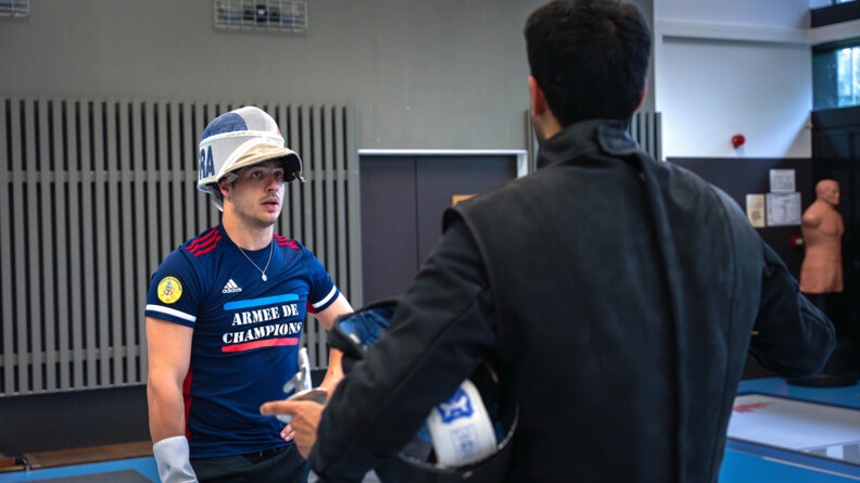 Face à son coach, casque relevé, Maxime Pauty le regarde qui s'entretient avec lui