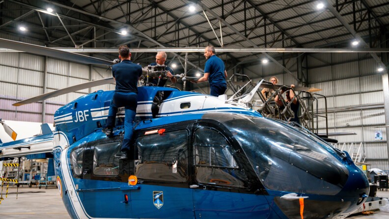 Agrandir l'image Trois gendarmes en train de monter les pales d'un hélicoptère EC145 de la gendarmerie dans un hangar