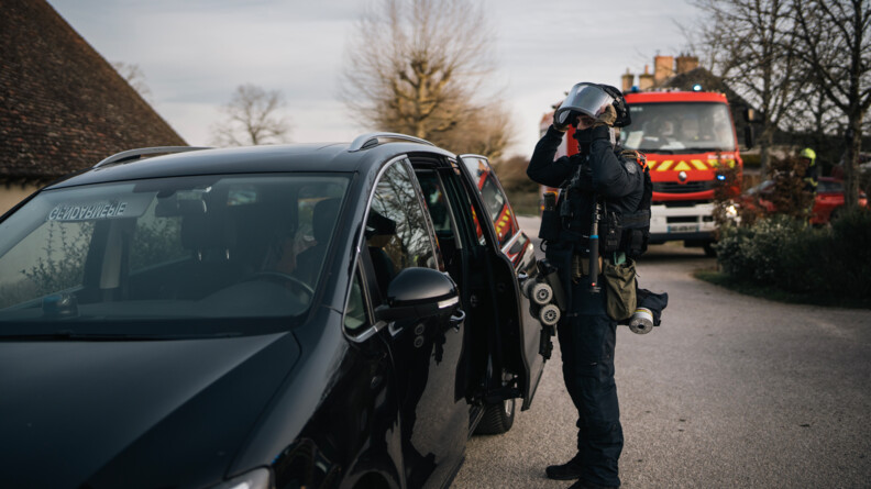 1 opérateur AGIGN s'équipe, un camion de pompiers en arrière plan