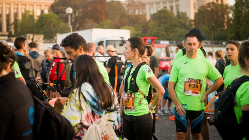 Des coureurs sont réunis dans l'attente du départ. Ils portent un t-shirt vert fluo