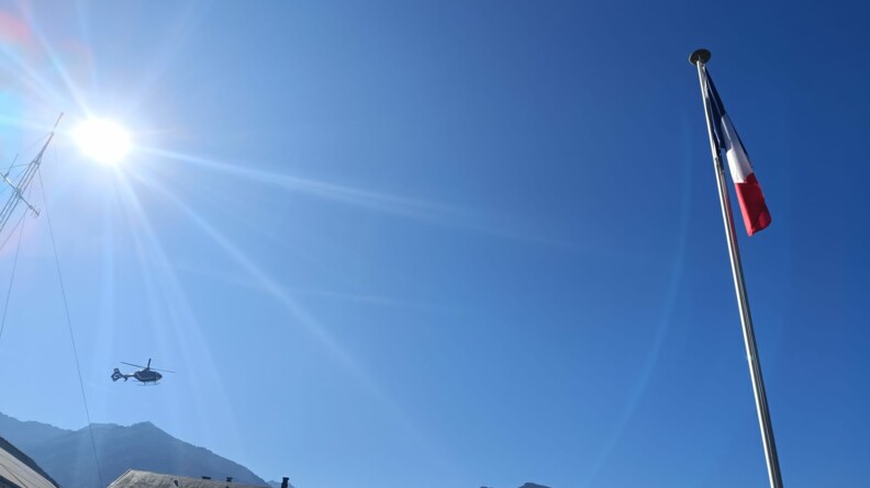 Vu du ciel avec le drapeau de la brigade et en fond, dans le ciel, un hélicoptère de la gendarmerie.
